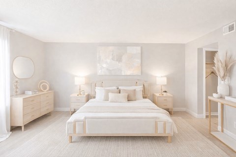 A white bedroom with a large bed, nightstands, and a painting on the wall.