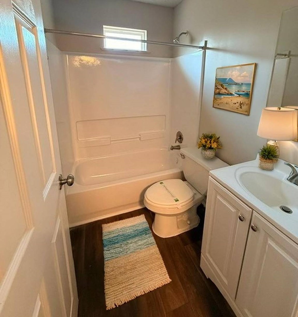 A bathroom with a toilet, sink, and a painting on the wall.