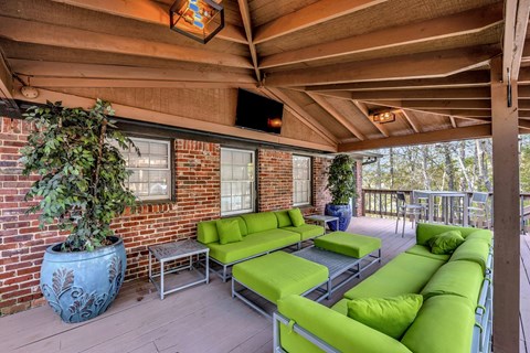 a covered porch with green couches and plants