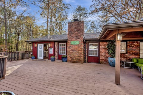 the front porch of a brick house with a wooden deck