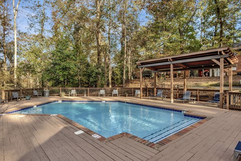 a resort style swimming pool with a wooden deck and a pool pavilion