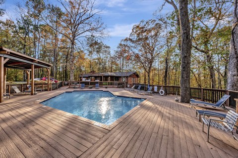 a backyard with a pool and a deck with chairs