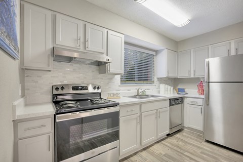 a white kitchen with stainless steel appliances and white cabinets
