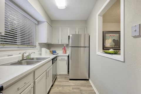 a kitchen with white cabinets and a stainless steel refrigerator