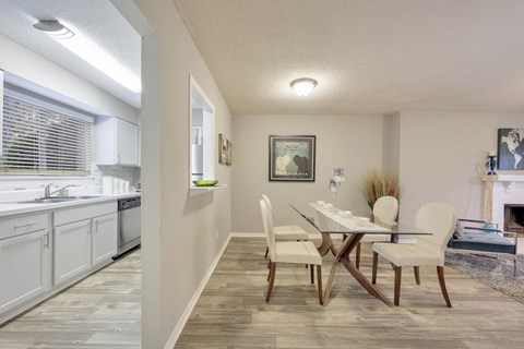 a dining room and kitchen with white cabinets and a table and chairs