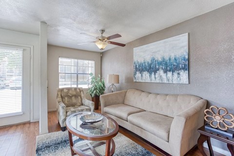 A living room with a beige couch, a coffee table, and a painting on the wall.