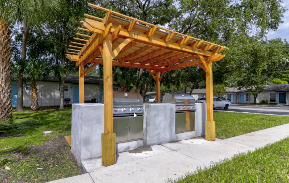 a pergola with two bbq grills in a yard