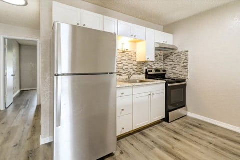 a white kitchen with a stainless steel refrigerator