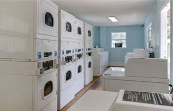 a laundry room filled with white washers and dryers