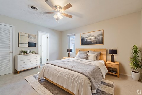 A bedroom with a bed, nightstand, and a ceiling fan.