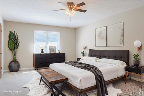 A bedroom with a bed, nightstand, and a plant.