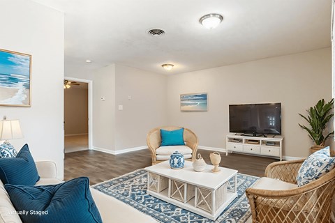 A living room with a white couch, a white coffee table, and a television.