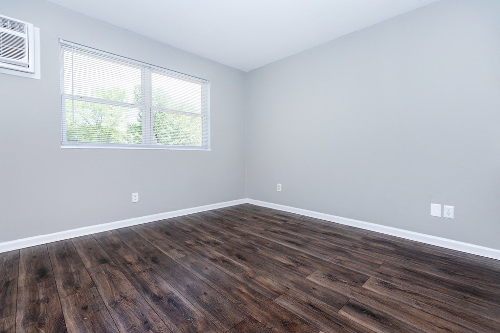 an empty room with wood floors and a window