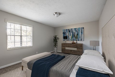 A bedroom with a bed, a dresser, and a plant.