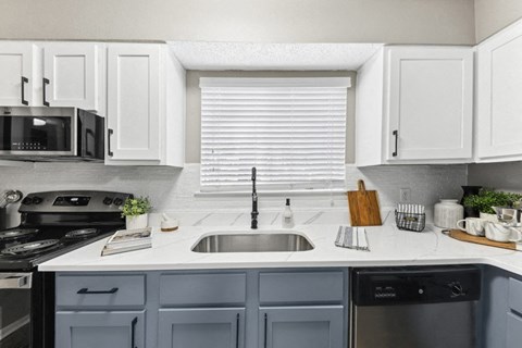 a white kitchen with blue cabinets and a sink