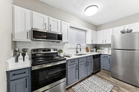 an open kitchen with stainless steel appliances and white cabinets