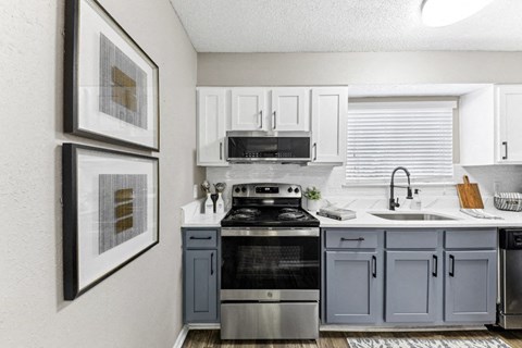 an open kitchen with white cabinets and black appliances and a window