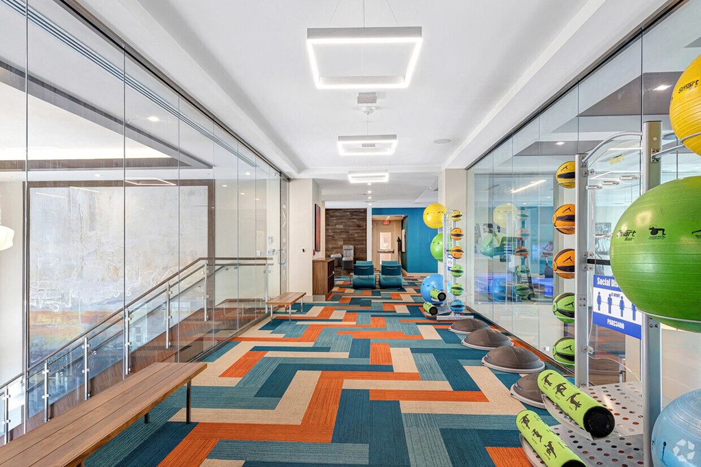 a long hallway with glass walls and a colorful carpet on the floor