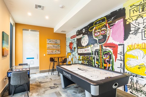 a game room with a pool table and graffiti on the wall