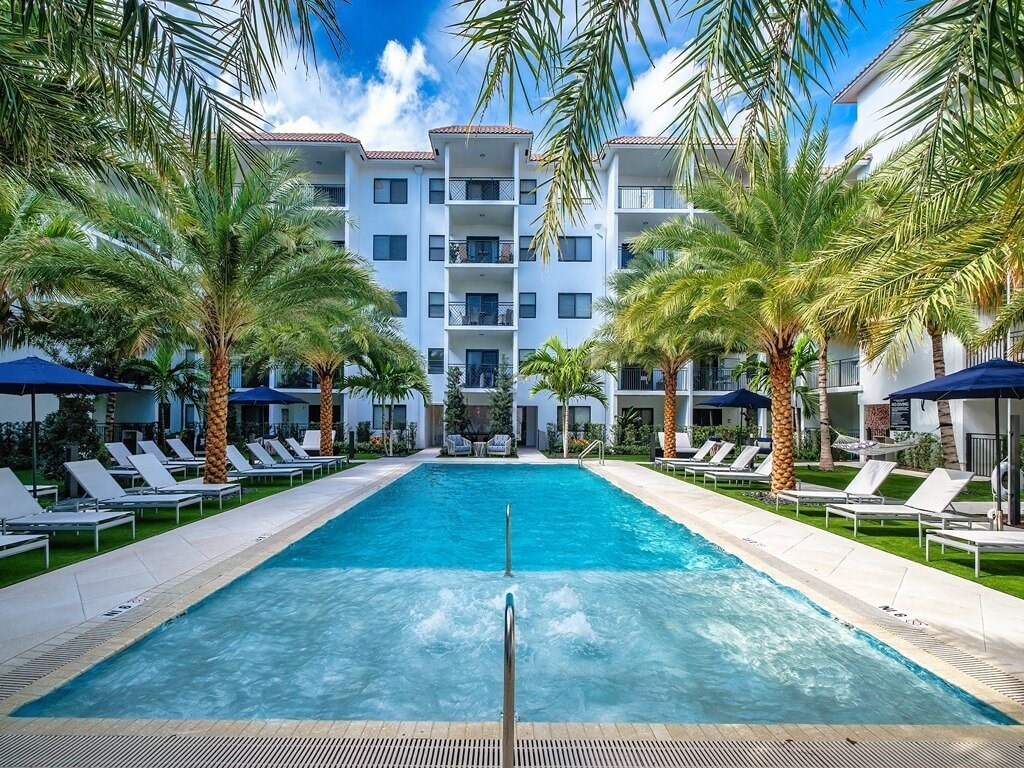 a large pool with palm trees in front of an apartment building