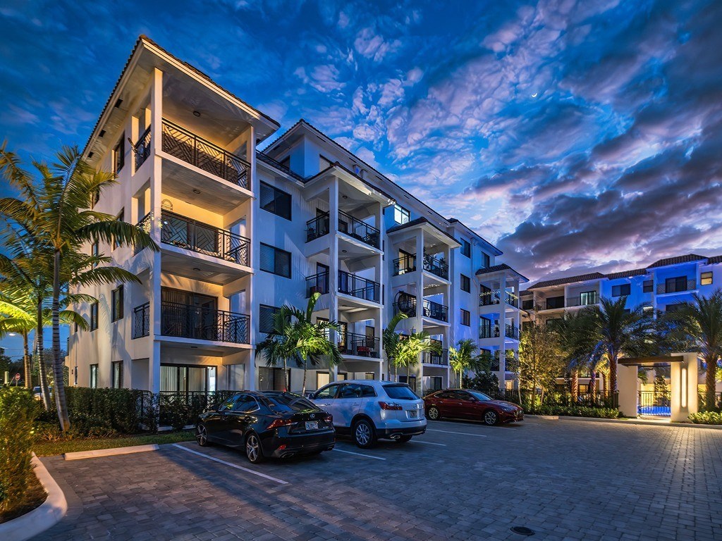 an apartment building at night with cars parked in front of it