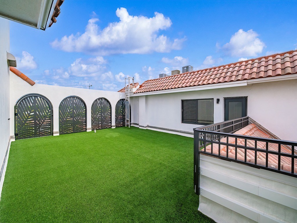 a backyard with a green lawn and a balcony