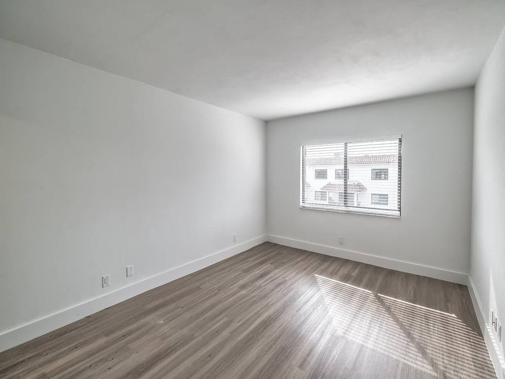 an empty living room with a window and wood floors