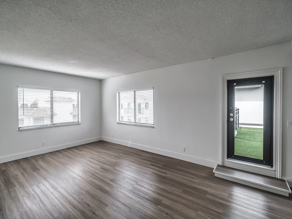 an empty living room with wood flooring and a window