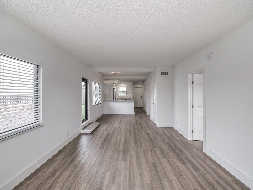 an empty living room with white walls and wood floors