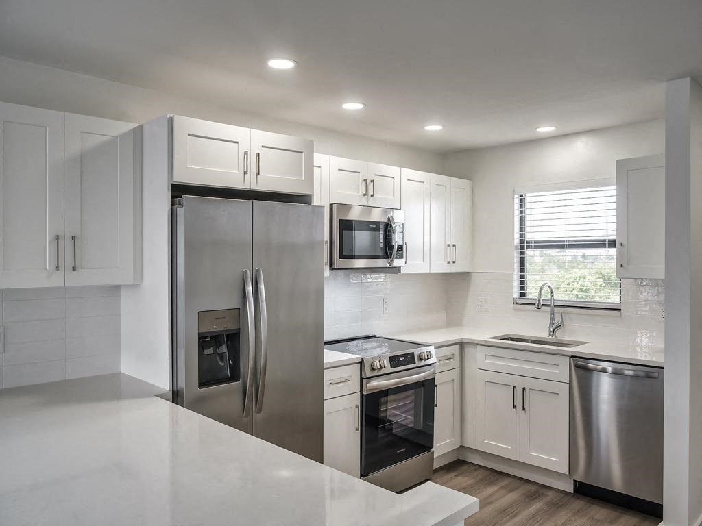a white kitchen with stainless steel appliances and white cabinets