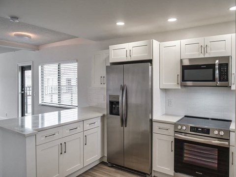 a kitchen with white cabinets and a stainless steel refrigerator