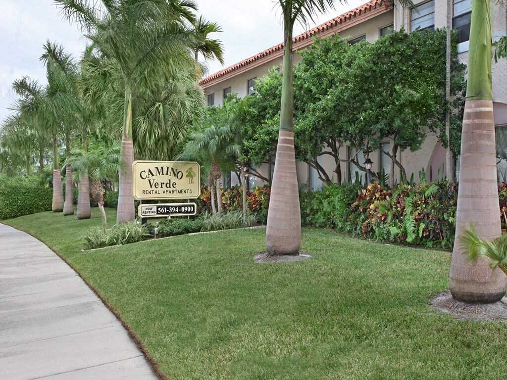 a sign in front of a building with palm trees