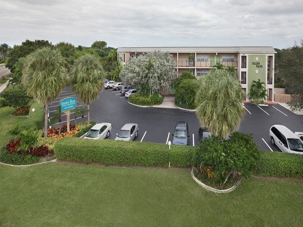 an aerial view of a parking lot with cars and palm trees