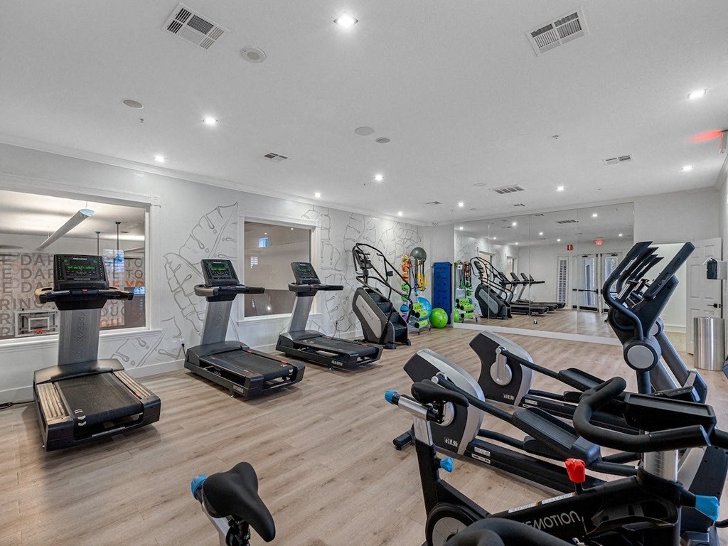 the gym has plenty of cardio equipment and a wall mural of graffiti