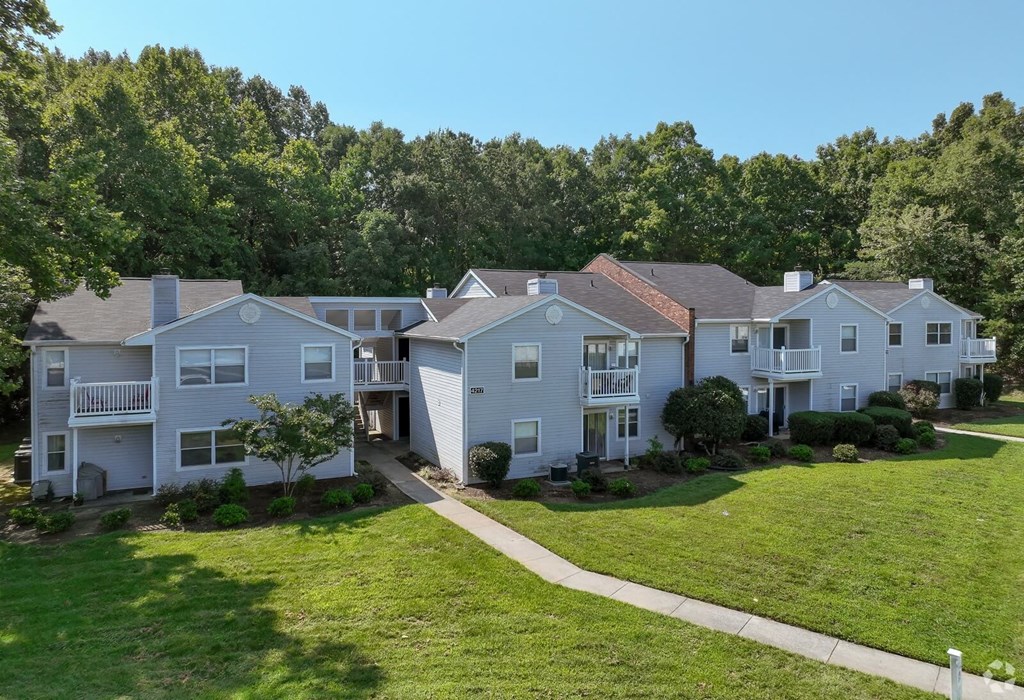 A row of white houses with green trees in the background. A row of white houses with green trees in the background at Sedgefield Square Apartments, Greensboro, 27407