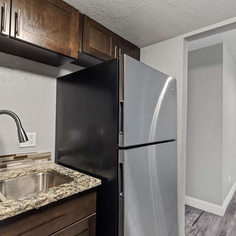 A black refrigerator in a kitchen with a granite countertop.