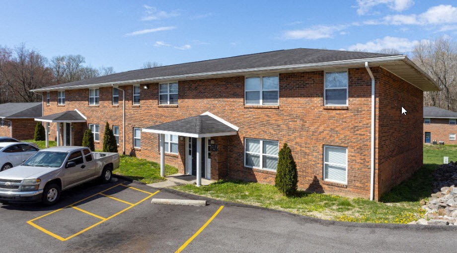 a brick building with a car parked in a parking lot