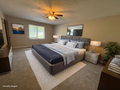 A bedroom with a large bed and a ceiling fan.