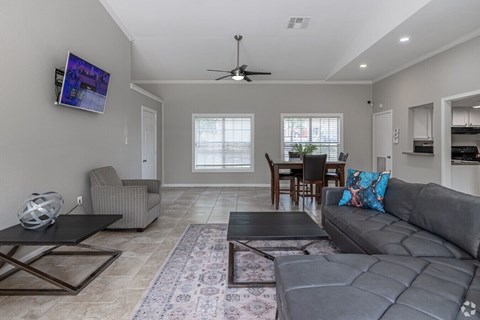 A living room with a grey couch, a black coffee table, and a television mounted on the wall.