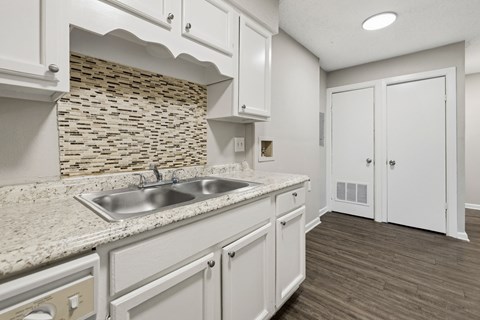 A kitchen with white cabinets and a stone backsplash.