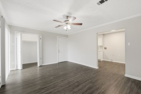 A spacious room with a ceiling fan and wooden flooring.