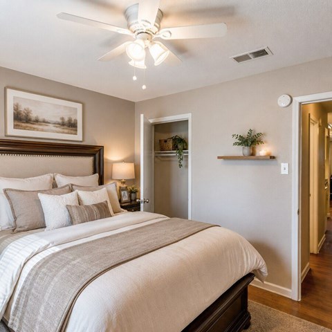 A bedroom with a large bed and a ceiling fan.