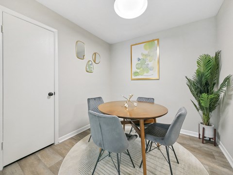 A dining room with a round table and grey chairs.