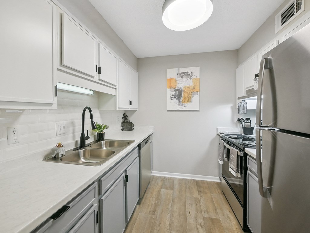 an apartment kitchen with stainless steel appliances and white cabinets