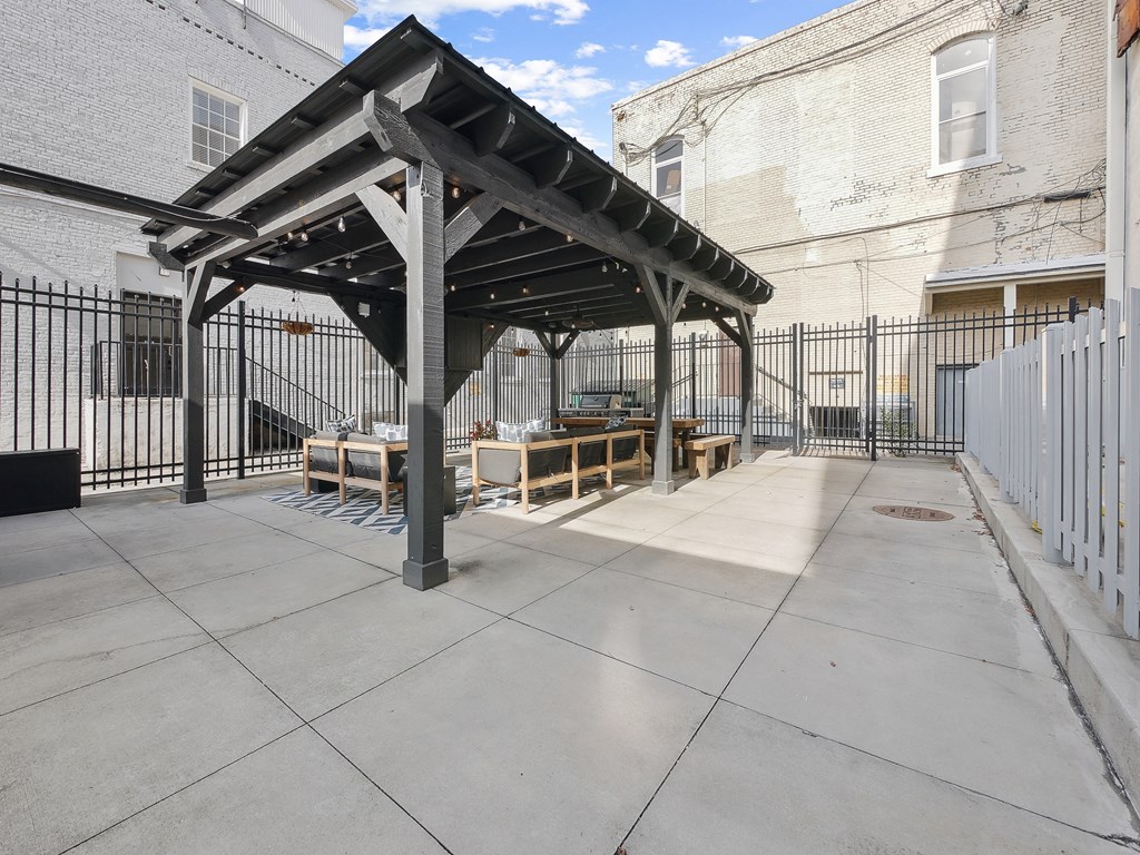 a patio with a table and chairs in front of a fence