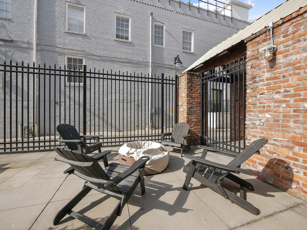 a patio with two chairs and a table in front of a brick building