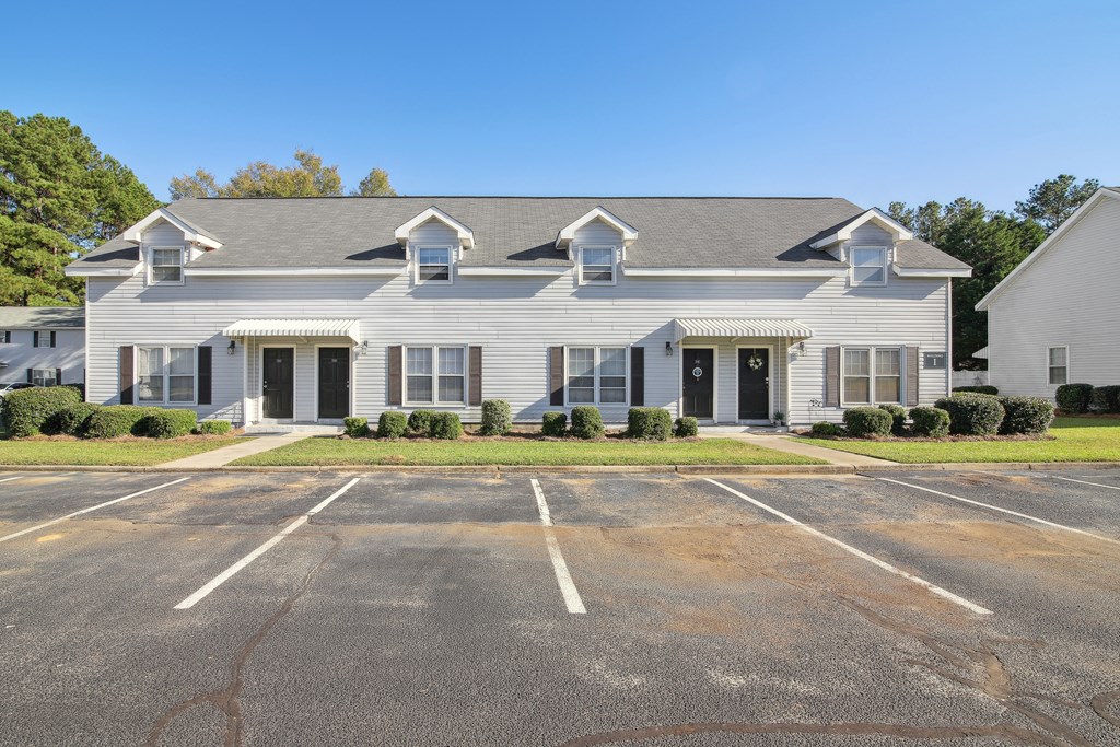 a white house with a parking lot in front of it