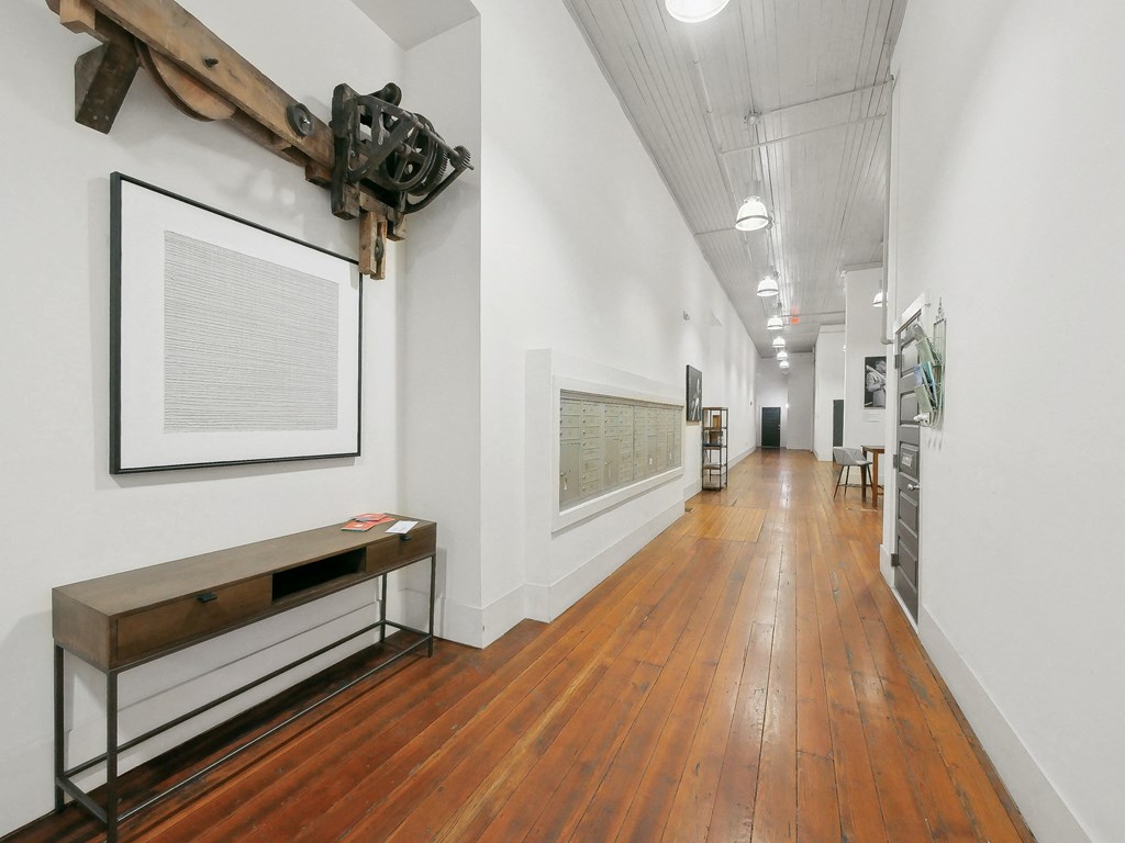 a long hallway with white walls and wood floors and a large artwork on the wall