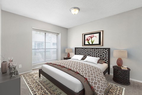 A bedroom with a large bed and a framed picture of a flower on the wall.