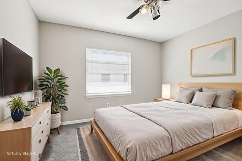 A bedroom with a bed, dresser, and ceiling fan.